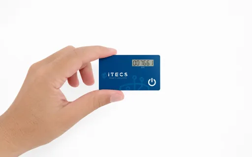 A hand holding an ITECS-branded card-shaped hardware token with a numeric display and power button.