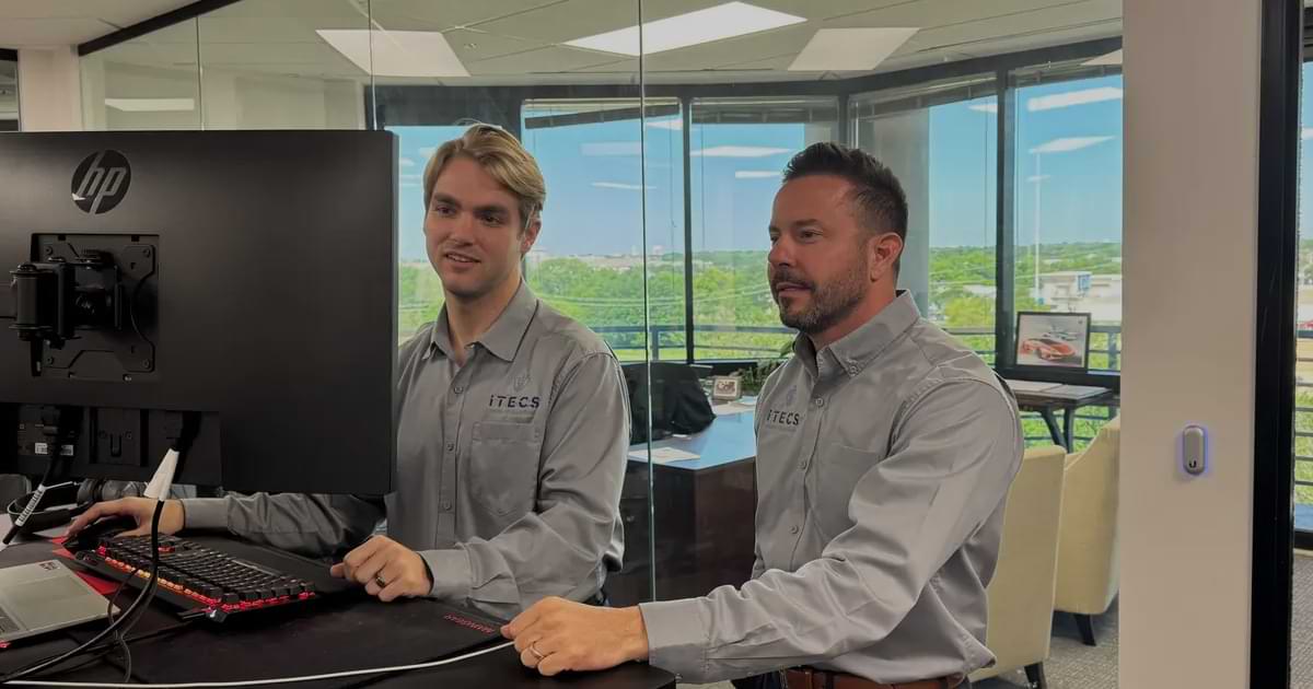 Two iTecs employees at modern standing desk workstation